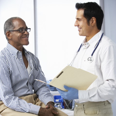 Doctor-In-Surgery-With-Male-Patient-Reading-Notes_web